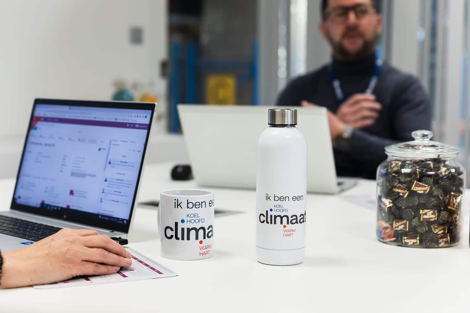 Een meeting is bezig bij Climatrix. Op de tafel staan verschillende laptops, een koffiemok en drinkfles van Climatrix.