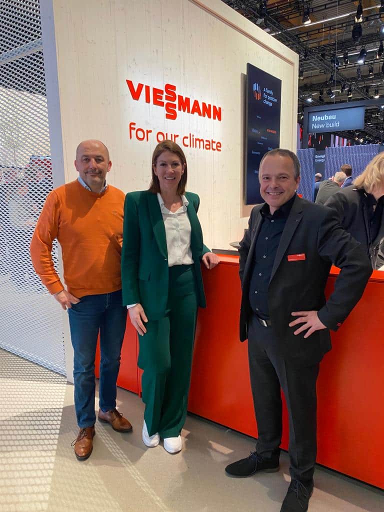 Climatrix werkt samen met Viessmann. Kim Vaessen poseert samen met medewerkers bij het logo van Viessmann, op een beurs.